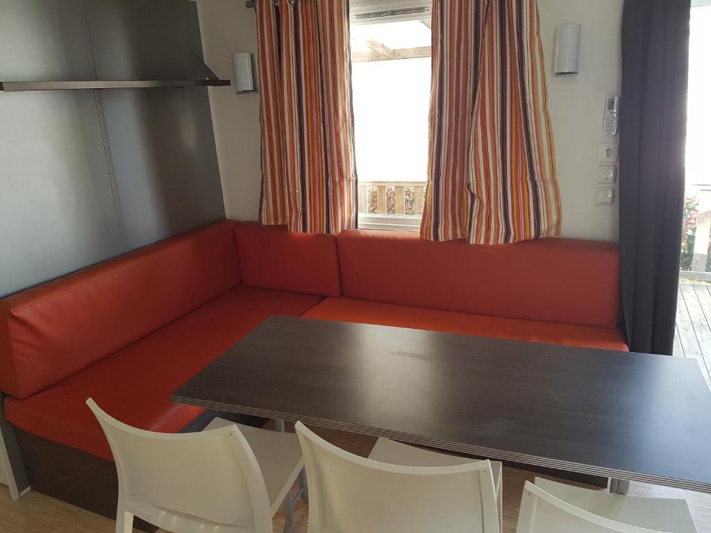 - un salon avec un canapé rouge, une table et des chaises dans l'établissement Mobil Home Camping des 7 Fonts, à Agde 3 autres photos