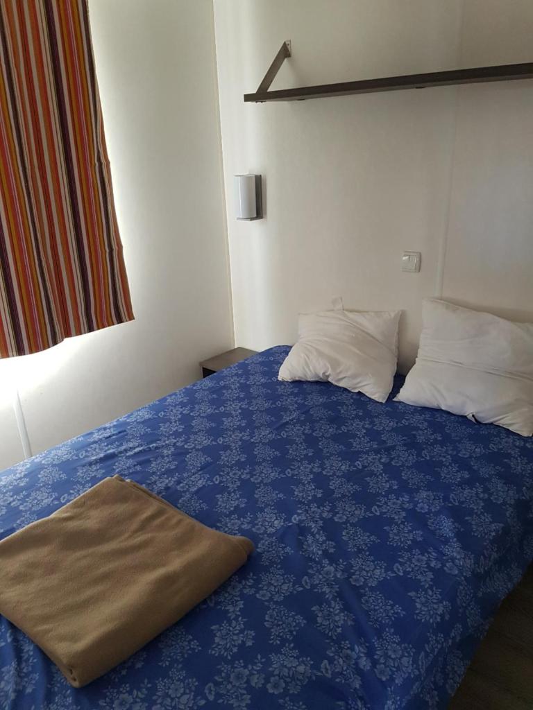 - une chambre avec un lit bleu et 2 oreillers dans l'établissement Mobil Home Camping des 7 Fonts, à Agde