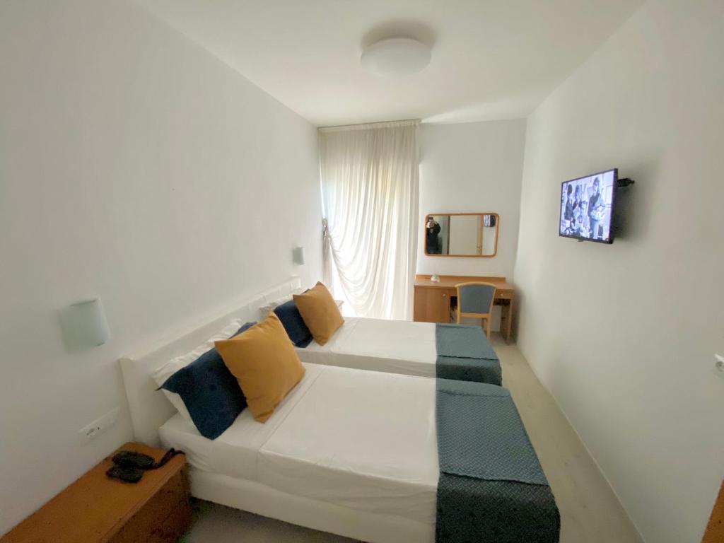 - une chambre dotée d'un lit blanc avec des oreillers jaunes et bleus dans l'établissement Hotel Cavallino Bianco, à Cavallino-Treporti