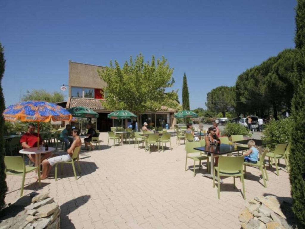 un groupe de personnes assises aux tables et aux chaises dans l'établissement La Roque d'Anthéron - Mobile-home - 6 pers - 3 ch - Piscine, à La Roque-dʼAnthéron