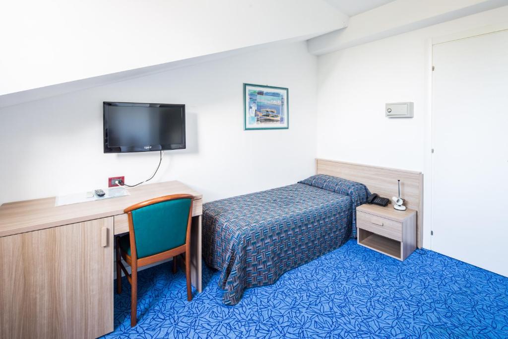 une chambre d'hôtel avec un lit, un bureau et une télévision dans l'établissement Hotel Olympia, à Lignano Sabbiadoro