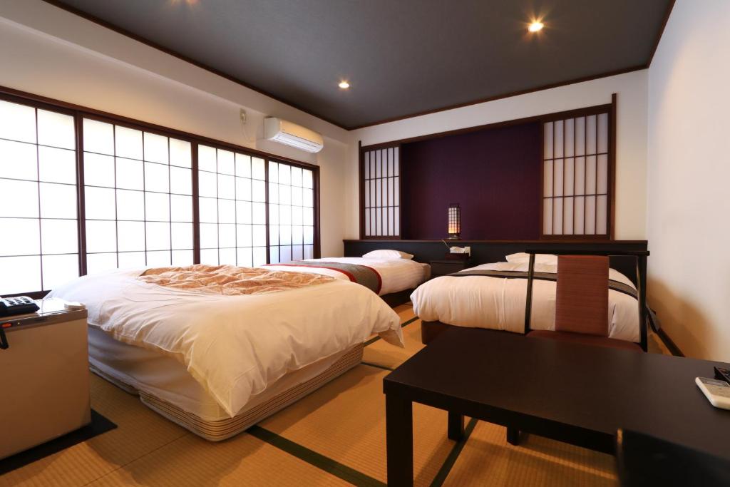 - une chambre avec 2 lits, une table et des fenêtres dans l'établissement Masuya Ryokan, à Izumo