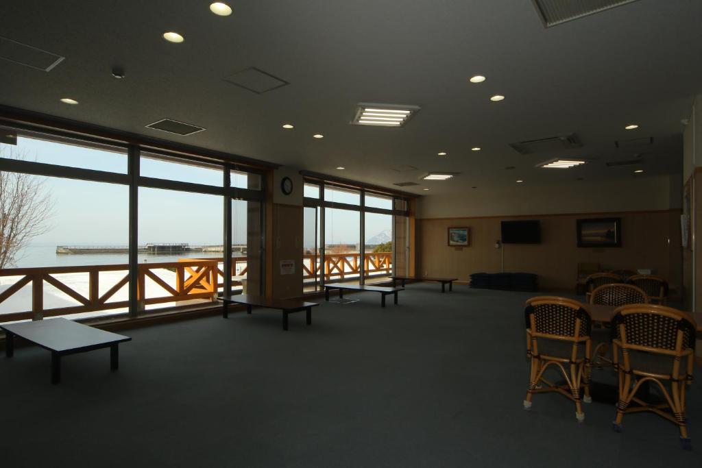 une grande chambre avec des chaises, des tables et des fenêtres dans l'établissement Spa SHIOSAI, à Toyoura