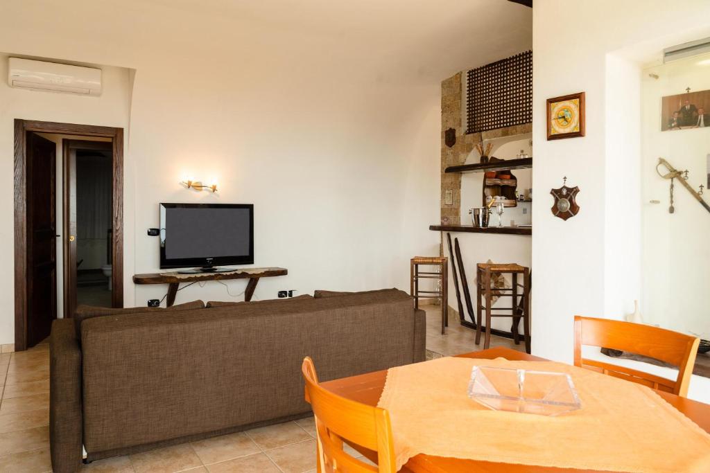 un salon avec un canapé, une table et une télévision dans l'établissement Villa immersa nel verde dell Etna, à Piedimonte Etneo