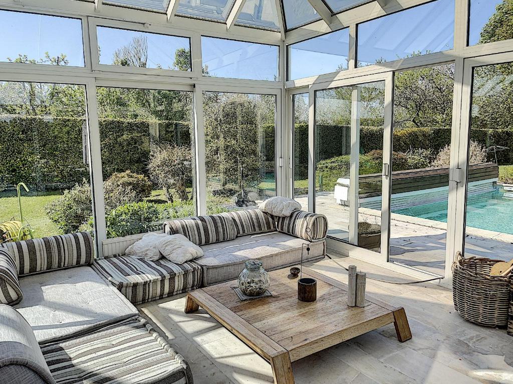 une véranda avec un canapé et une table basse dans l'établissement Gîte de charme "La Maison Saint-Leonard" avec piscine, SPA, vue sur le Mont Saint-Michel, à Vains