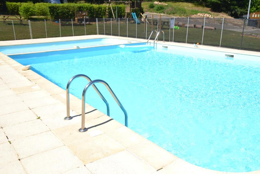 une grande piscine avec de l'eau bleue dans une cour dans l'établissement Camping Les Roussilles, à Saint-Sylvestre