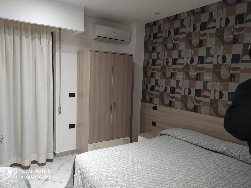 une chambre avec un lit et une armoire en bois dans l'établissement Hotel Poseidon, à Corigliano Calabro