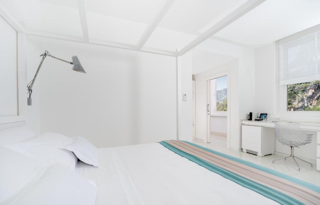 Cette chambre blanche comprend un lit et un bureau. dans l'établissement Casa Angelina, à Praiano