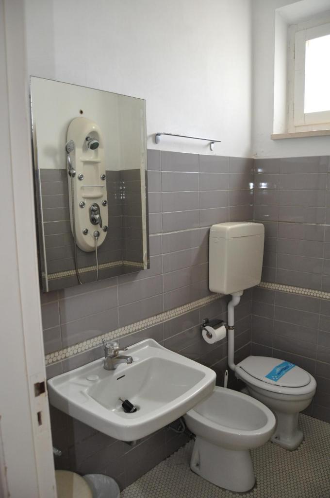 une salle de bain avec un lavabo, des toilettes et un miroir dans l'établissement Hotel Rigobello, à Riccione