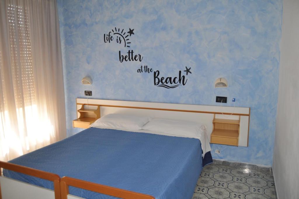 - une chambre dotée d'un lit avec les mots « la vie est meilleure à la plage » dans l'établissement Hotel Rigobello, à Riccione