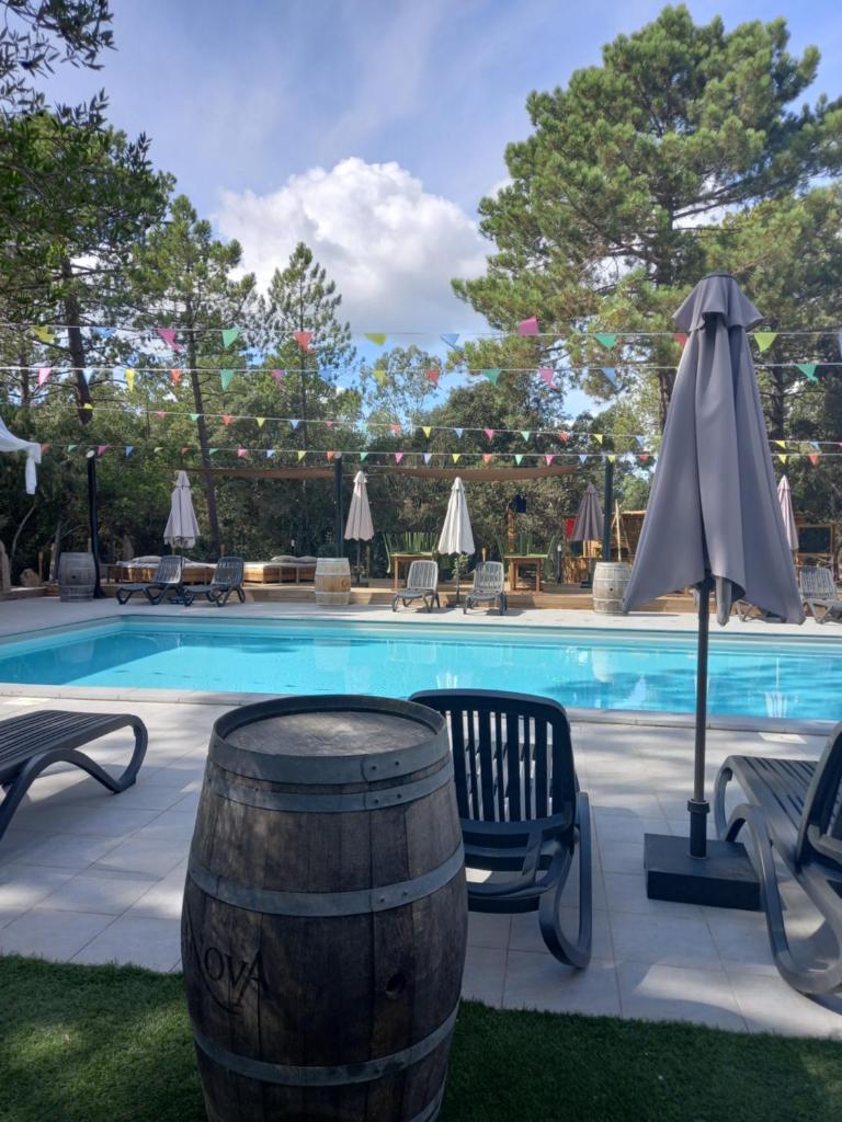 - une piscine avec un tonneau, un parasol, des chaises et une table dans l'établissement Camping U STABIACCIU, à Porto-Vecchio
