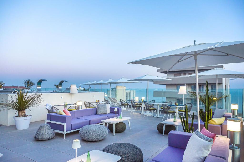 un patio avec des meubles violets, des tables et des parasols dans l'établissement J44 Lifestyle Hotel, à Lido di Jesolo