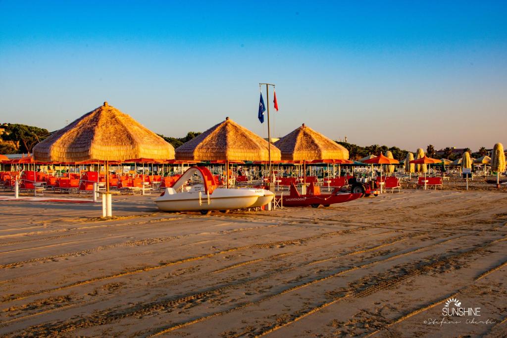 - une plage avec des parasols et un bateau sur le sable dans l'établissement Hotel Palace Magnolia SPA, à Tortoreto Lido