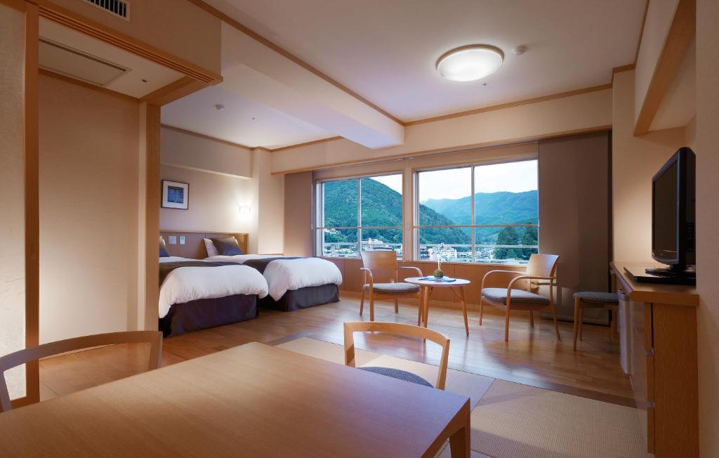 une chambre d'hôtel avec deux lits, une table et des chaises dans l'établissement Suimeikan, à Gero