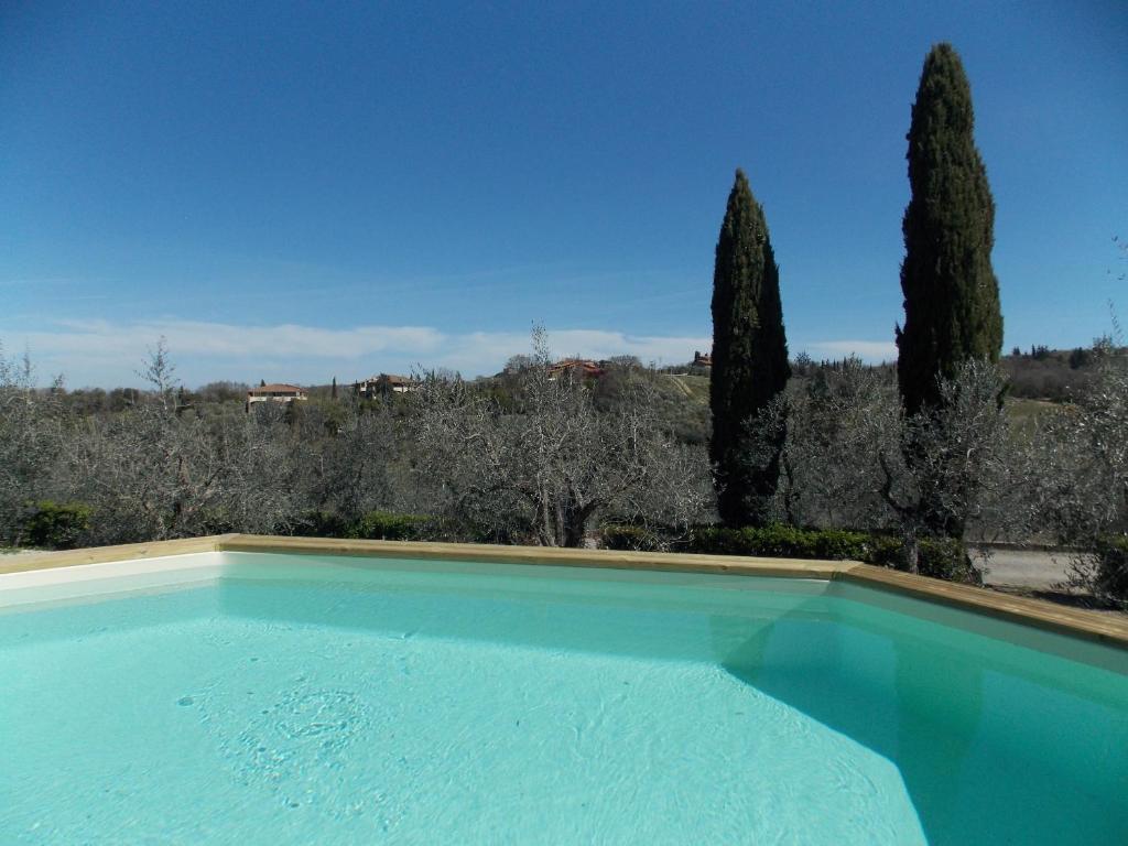une piscine bleue avec des arbres en arrière-plan dans l'établissement Pieve di Campoli by VacaVilla, à San Donato in Poggio