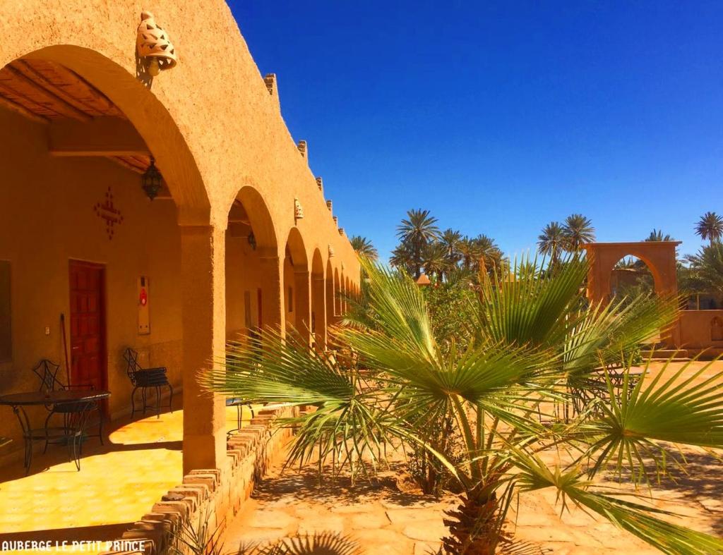 un bâtiment avec un palmier devant dans l'établissement Hotel Riad Le Petit Prince, à Merzouga
