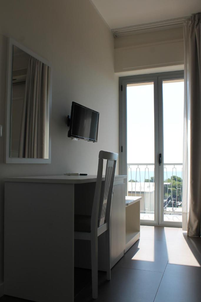 Cette chambre comprend un bureau avec une chaise et une télévision. dans l'établissement Hotel Corallo, à Villapiana