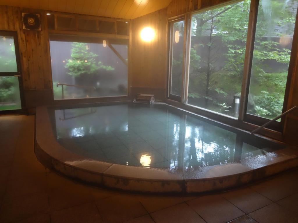 un jacuzzi dans une pièce avec des fenêtres dans l'établissement Kusatsu Skyland Hotel, à Kusatsu 87 autres photos