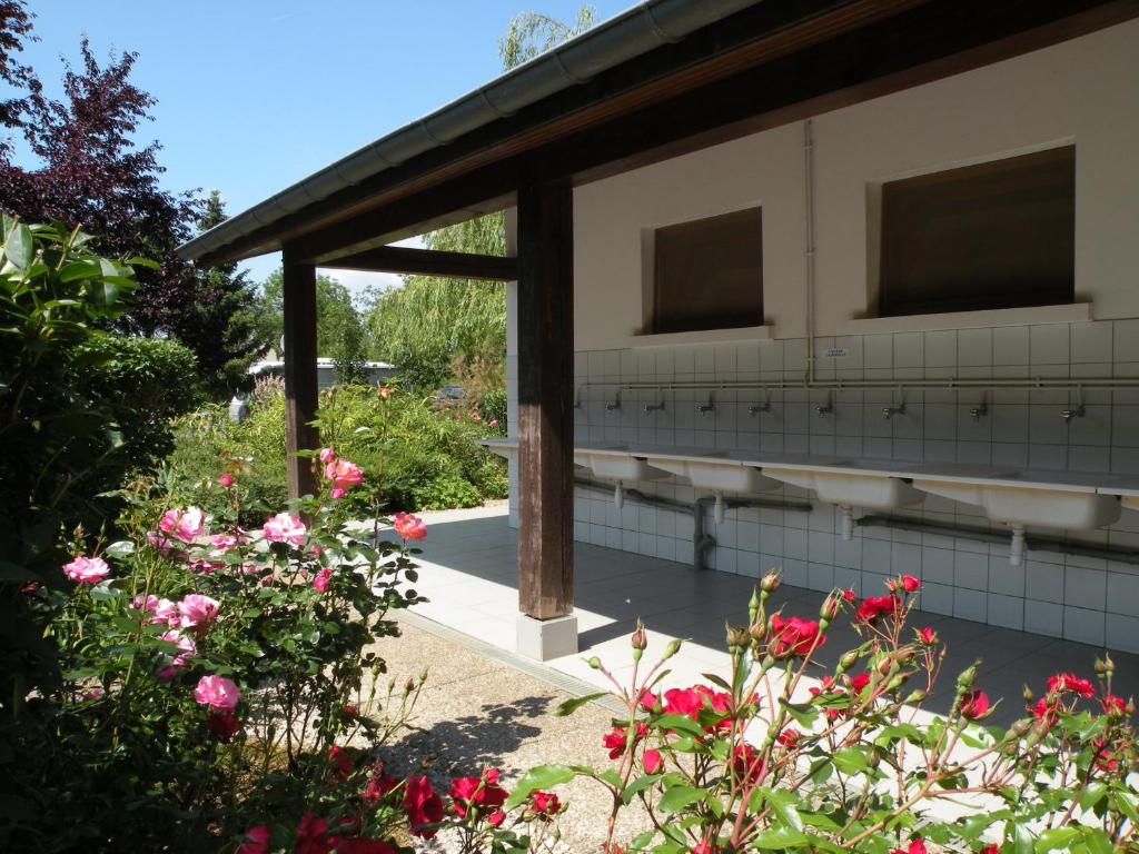 un jardin avec des fleurs roses et un bâtiment dans l'établissement Tente Familiale au Camping Hautoreille, à Bannes 5 autres photos