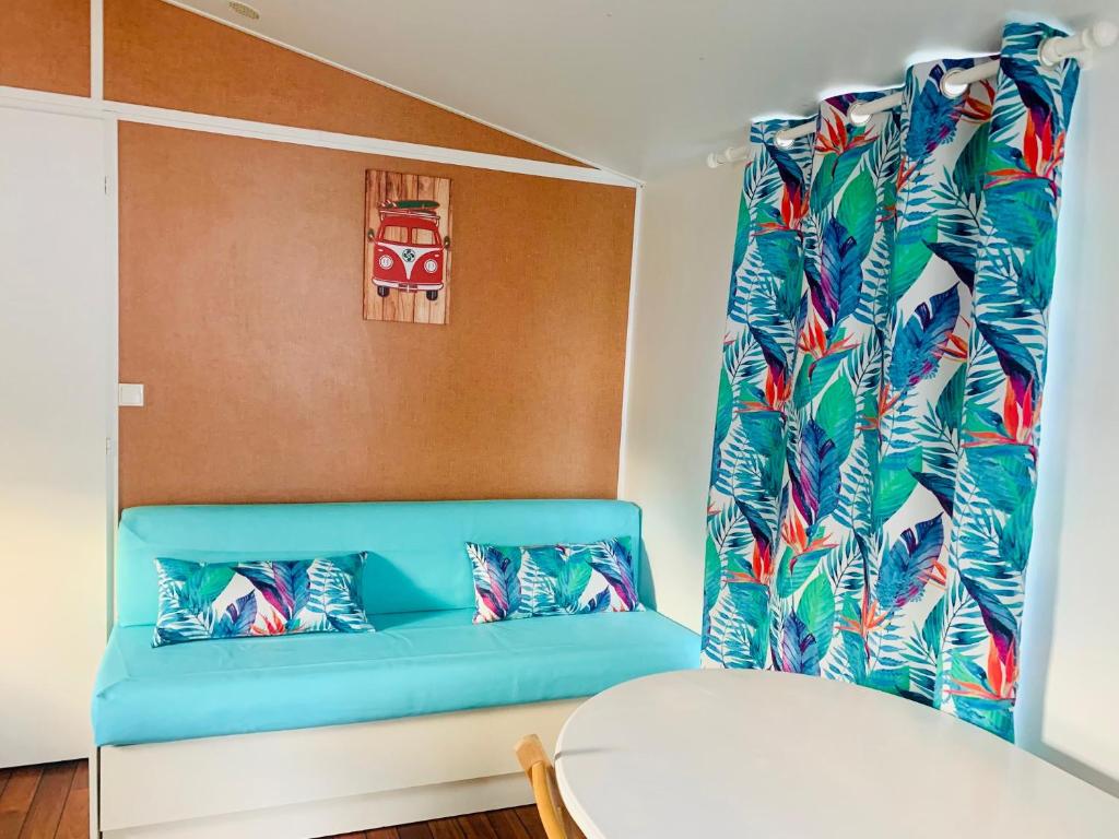une chambre avec un canapé bleu et une fenêtre dans l'établissement Camping Airotel le Sen-Yan, à Mézos