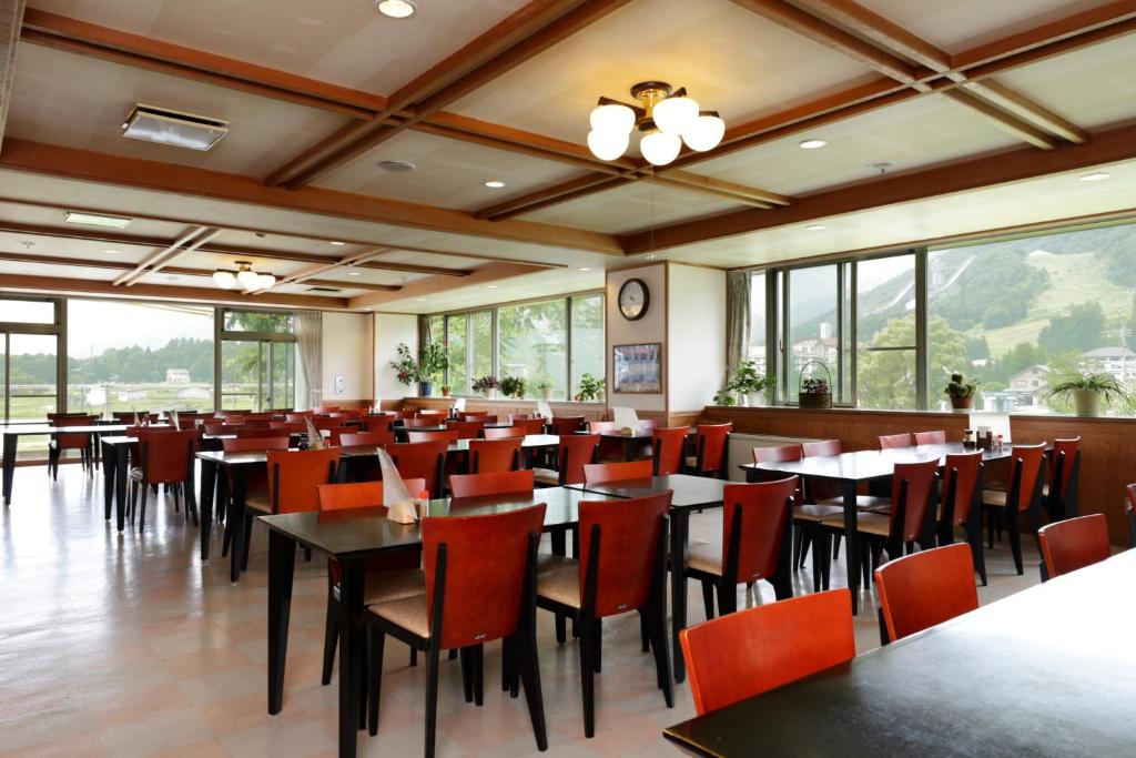 une salle à manger avec tables, chaises et fenêtres dans l'établissement Happokan, à Hakuba