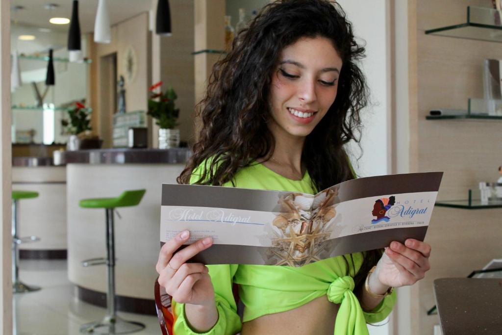 une femme en robe verte lisant un livre dans l'établissement Hotel Adigrat, à Riccione 122 autres photos