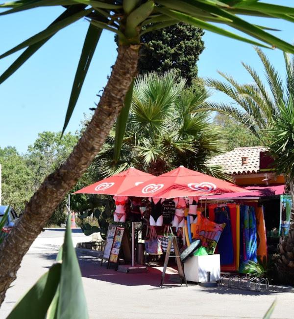 un magasin avec un parapluie rouge à côté d'un palmier dans l'établissement Mobil Home Hyères les palmiers, à Hyères