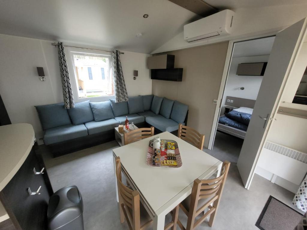 un salon avec une table et un canapé bleu dans l'établissement GUIG99 camping les dunes de Contis, à Saint-Julien-en-Born