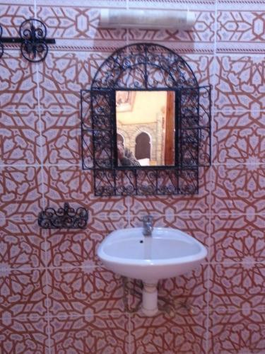 une salle de bain avec un lavabo et un miroir sur un mur dans l'établissement Hotel Riad Le Petit Prince, à Merzouga