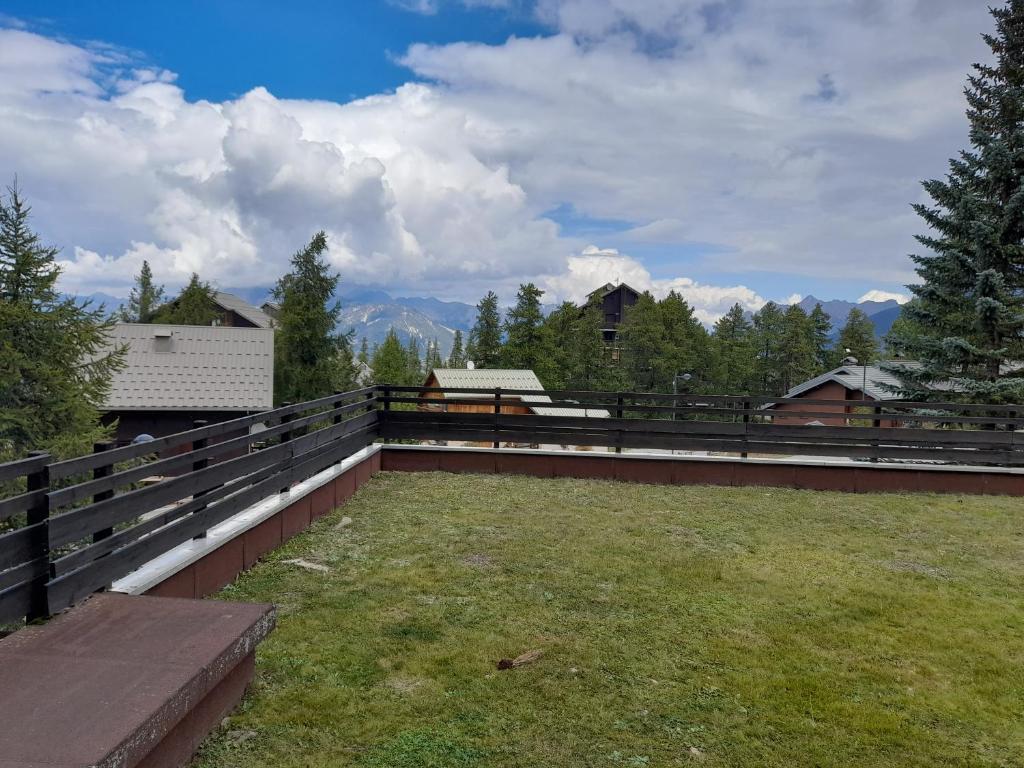 d'une terrasse avec une clôture et un champ d'herbe. dans l'établissement Risoul 1850 appartement 4 personnes proches pistes., à Risoul