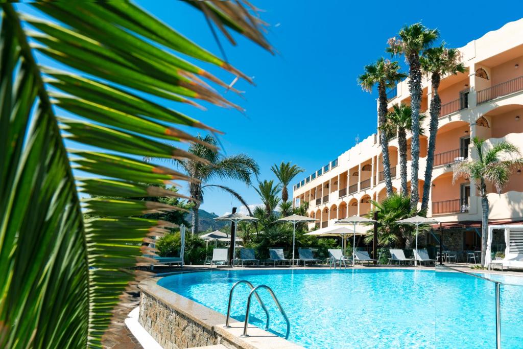 une piscine dans un complexe hôtelier avec des palmiers dans l'établissement Hotel Stella Maris, à Villasimius