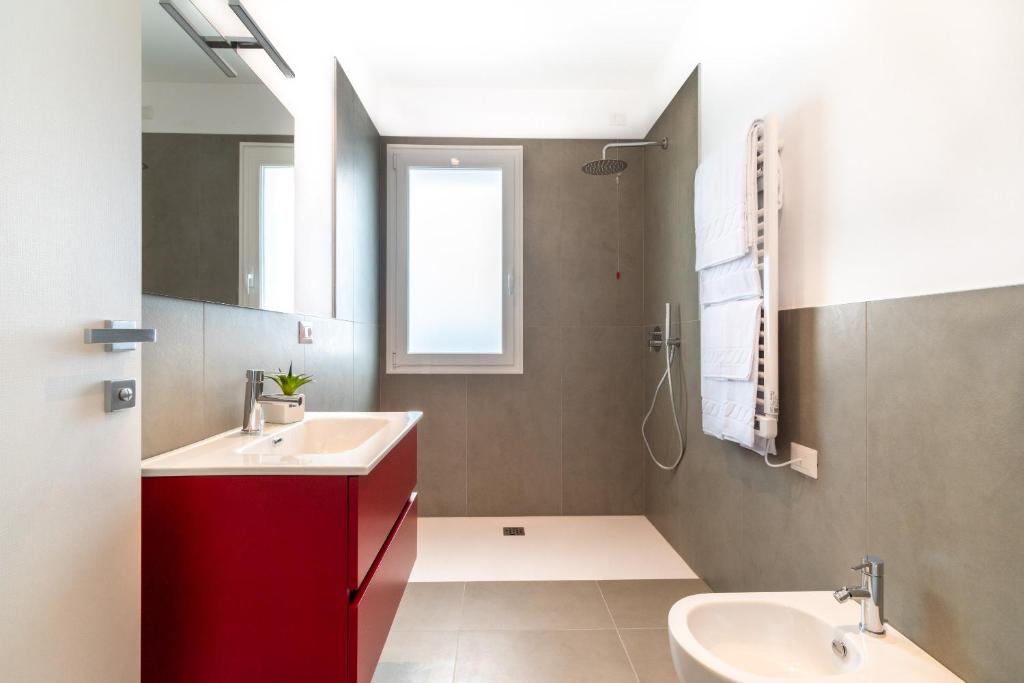 La salle de bains est pourvue de 2 lavabos et d'une armoire rouge. dans l'établissement Superior Beach Aparthotel, à Lido di Jesolo 65 autres photos