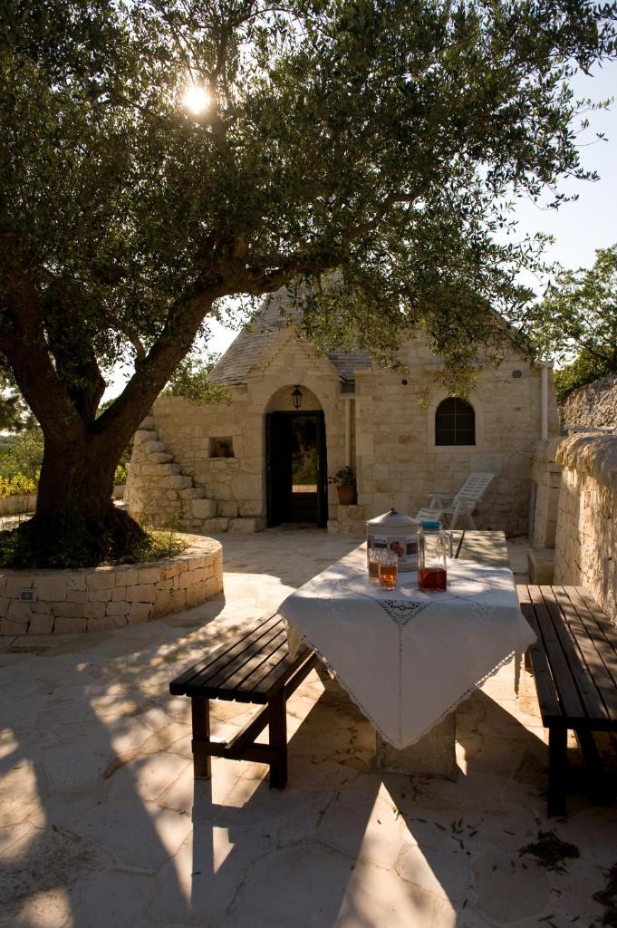 une table de pique-nique et un banc sous un arbre dans l'établissement Villa Trullo Panorama, à Locorotondo