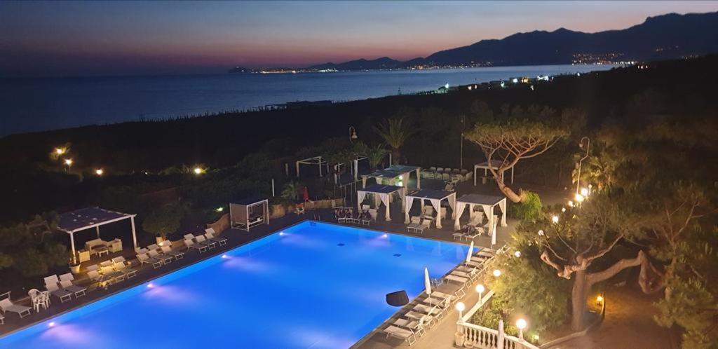 - une vue sur la piscine la nuit dans l'établissement Domizia Palace Hotel, à Baia Domizia
