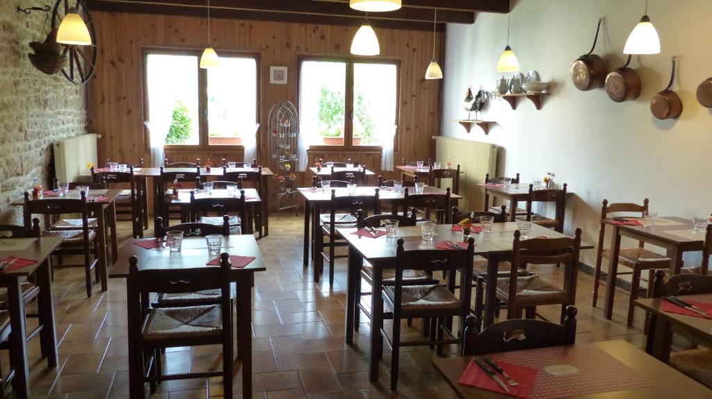 un restaurant avec des tables et des chaises en bois et des fenêtres dans l'établissement Tente Cabane du Camping Hautoreille, à Bannes