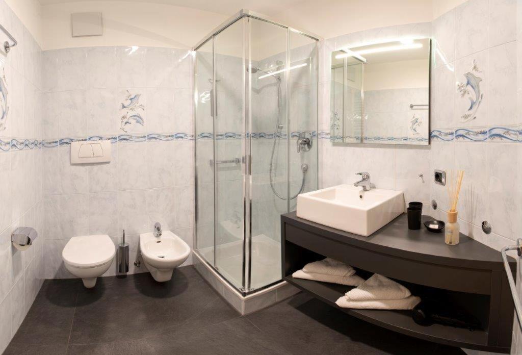 une salle de bain avec un lavabo, des toilettes et une douche dans l'établissement Residence Roland, à Caldaro