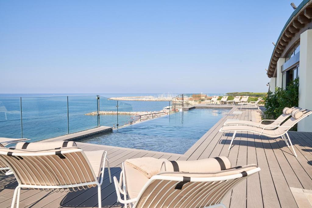 une terrasse avec des chaises et une piscine avec l'océan dans l'établissement Palace Lido Hotel & Suites, à Marina di Cecina