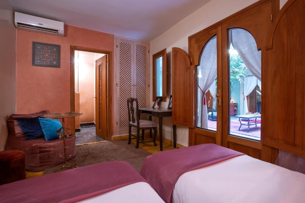 une chambre avec un lit, un bureau et une fenêtre dans l'établissement Riad l'Heure d'Eté, à Marrakech