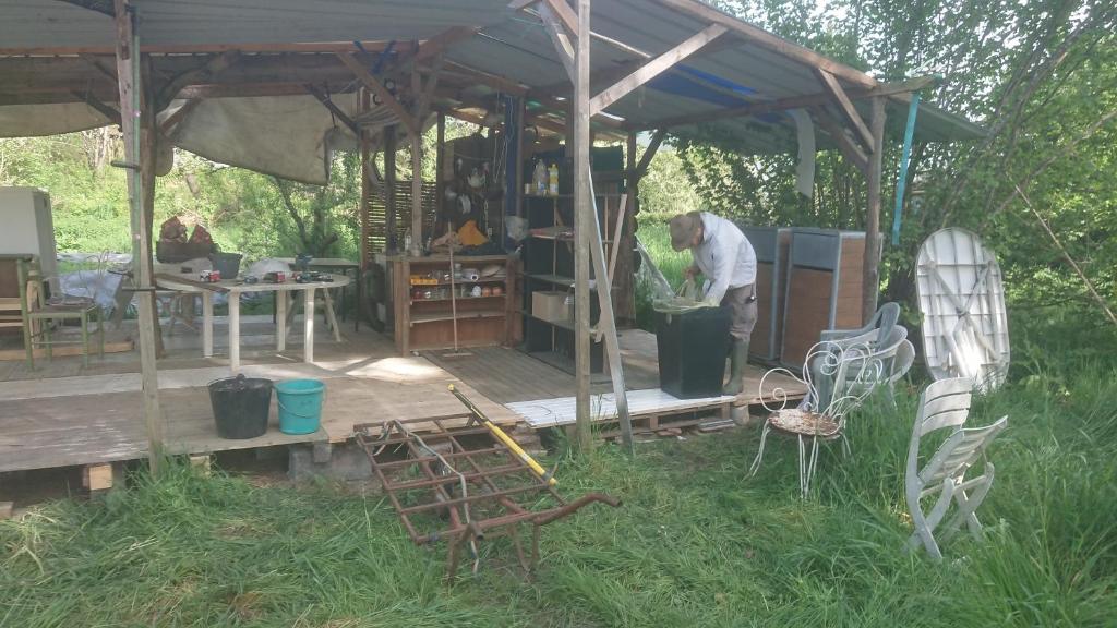 un homme debout sur une terrasse en bois sous une tente dans l'établissement Yourte rustique en permaculture, à Creysse
