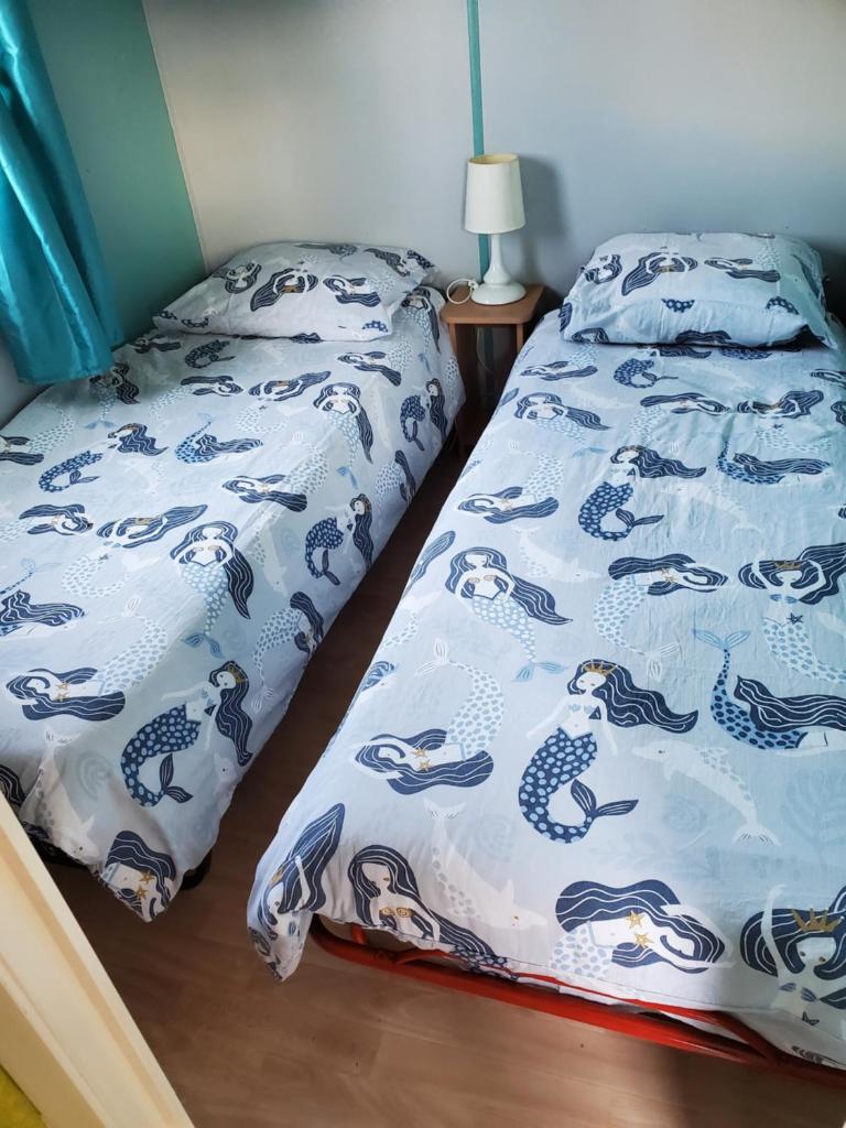 une chambre avec un lit avec un couvre-lit bleu et blanc dans l'établissement Mobil home chez l habitants, à Saint-Jean-de-Monts
