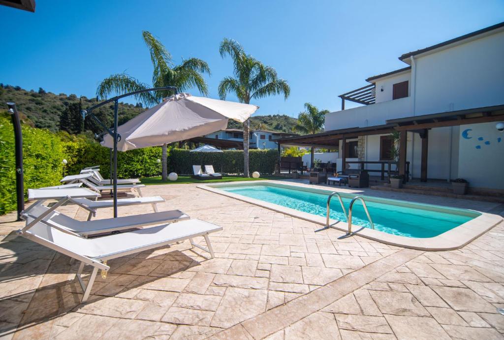 une piscine avec deux chaises longues et un parasol dans l'établissement Deluxe Sicily Villa, à Buonfornello