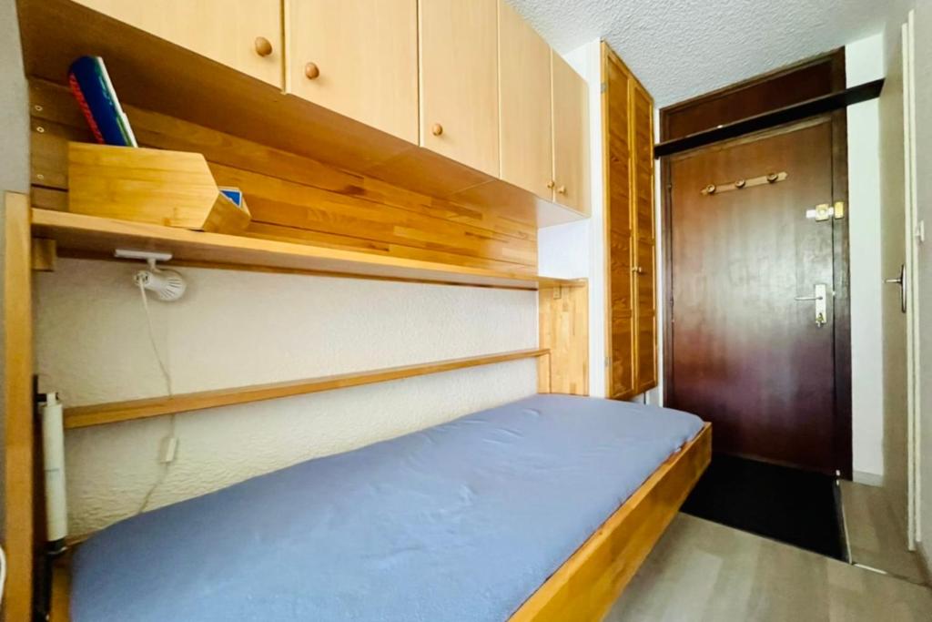 Cette petite chambre comprend un lit bleu et une porte. dans l'établissement Nice 28m Comfort In The Heart La Salle Les Alpes, à La Salle Les Alpes
