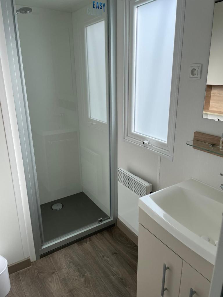 une salle de bain avec une douche avec une porte vitrée dans l'établissement MOBIL HOME VALRAS PLAGE LES SABLES DU MIDI, à Valras-Plage