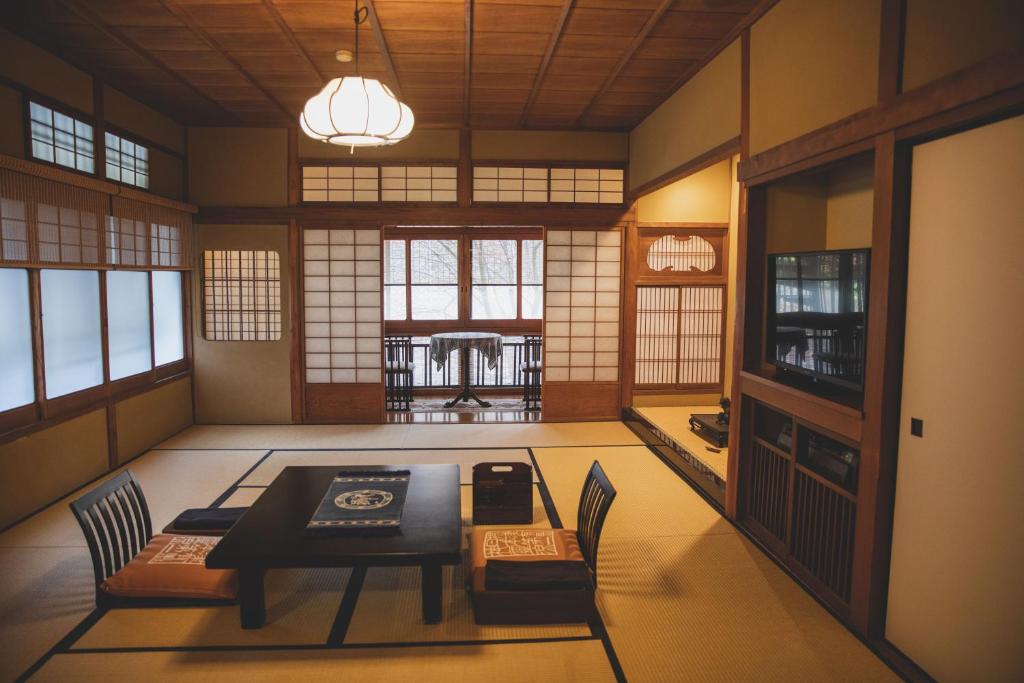 une salle à manger avec une table, des chaises et des fenêtres dans l'établissement Arima Onsen Tocen Goshobo, à Kobe