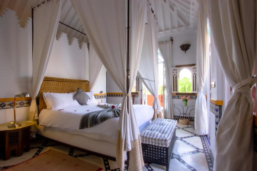 une chambre avec un lit à baldaquin avec rideaux dans l'établissement Riad Kaiss By Anika, à Marrakech