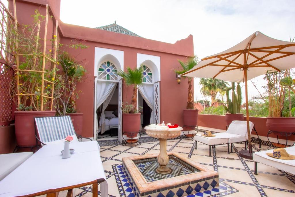 une terrasse avec des chaises blanches et un parasol dans l'établissement Riad Kaiss By Anika, à Marrakech