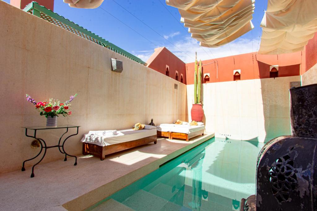 - une piscine avec 2 lits et une table à côté d'un bâtiment dans l'établissement Riad Kaiss By Anika, à Marrakech