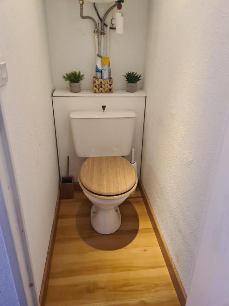 Elle comprend une petite salle de bains pourvue de toilettes et d'un siège en bois. dans l'établissement grand studio 28 m2 tout confort au pieds des pistes, à La Foux
