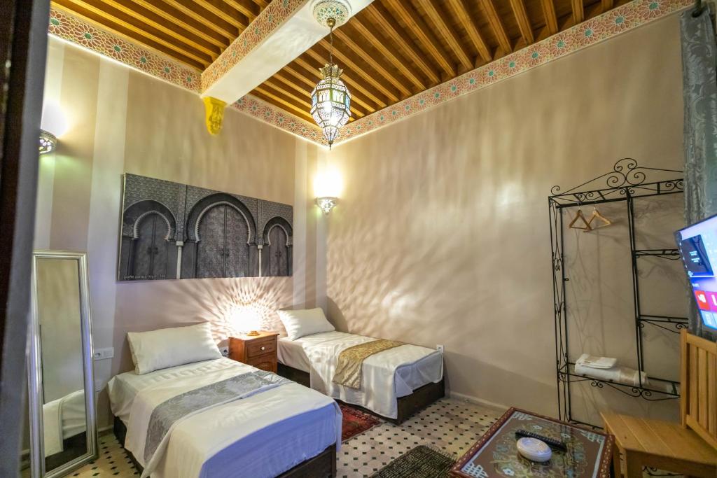 une chambre avec deux lits et une télévision dans l'établissement Riad Noha, à Fès