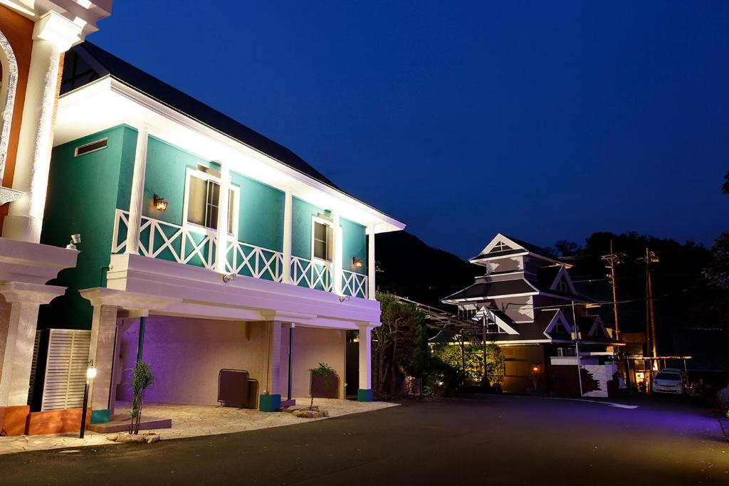 - un bâtiment vert et blanc la nuit dans l'établissement HOTEL555 伊豆長岡, à Izunokuni